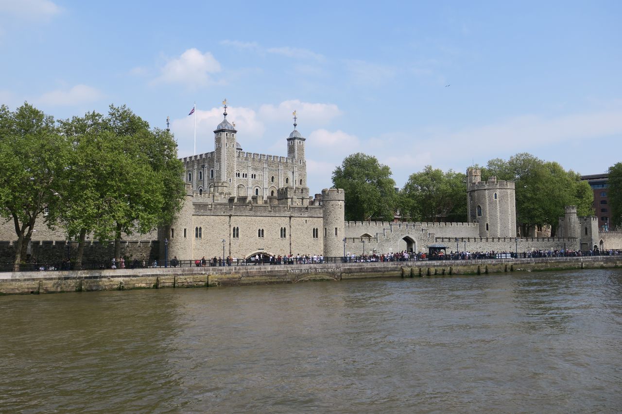 Historic Tower of London beside the River Thames on a clear day.