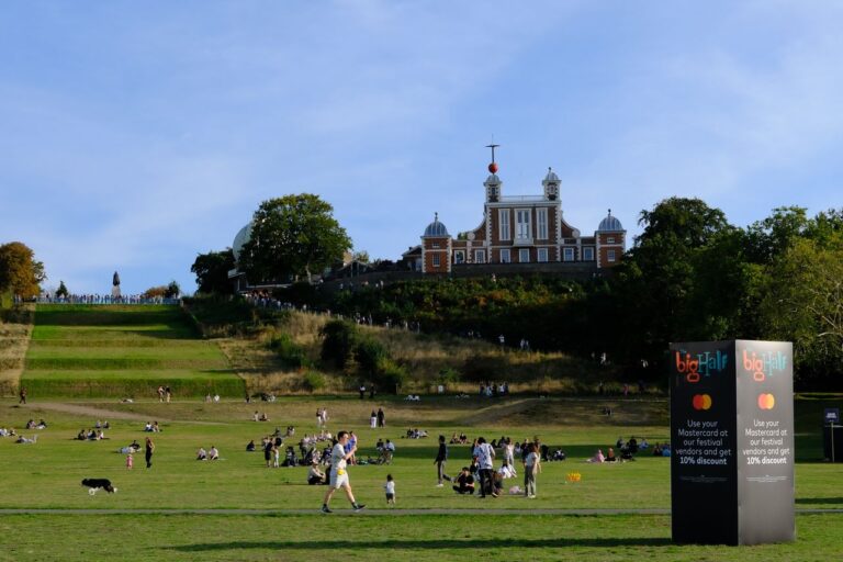 A vibrant scene at Greenwich Park with the historic Royal Observatory in London on a sunny day.