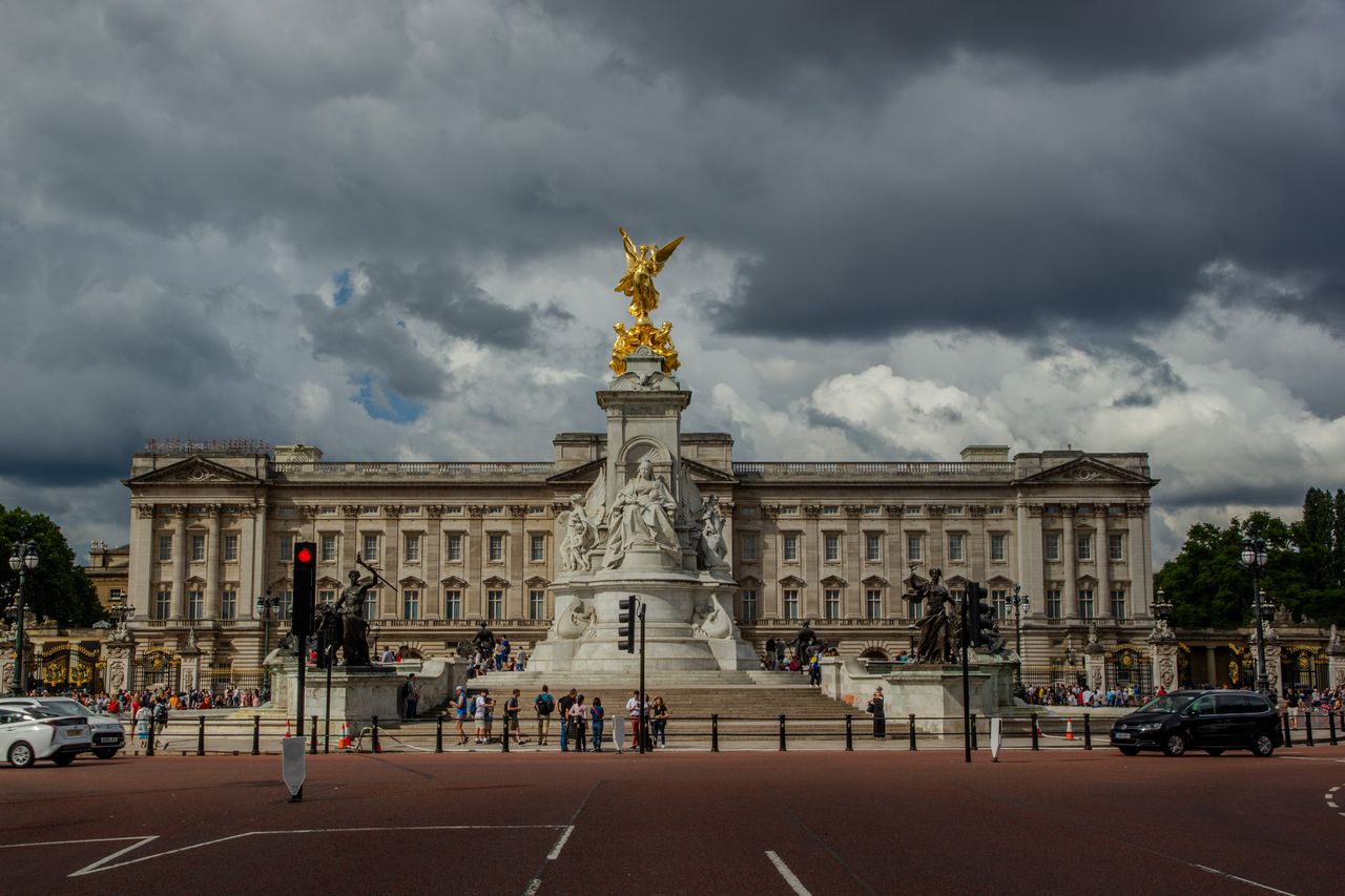 View of Buckingham Palace and Victoria Memorial under dramatic sky in London.